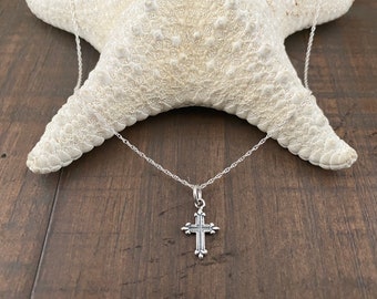 May include: A silver chain necklace with a small, ornate silver cross pendant.