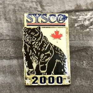 May include: Rectangular pin with a black bear illustration, a red maple leaf, and the text "SYSCO 2000". The pin has a gold border with blue and red accents. The bear is detailed with white outlines.