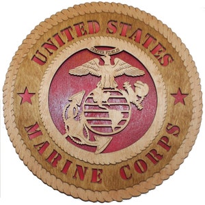 May include: A wooden wall plaque with a red, white, and blue United States Marine Corps emblem. The emblem features a globe, an anchor, and an eagle with the words "Semper Fidelis" above it. The words "United States Marine Corps" are written around the emblem.