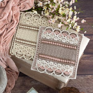 May include: Two crocheted squares, one in beige and one in brown with pink accents. Both squares feature a delicate lace border and intricate stitch patterns.