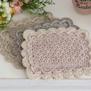 Scalloped crocheted Mug Rug pile with coffee cups and flowers.