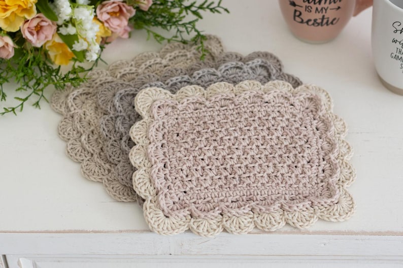Scalloped crocheted Mug Rug pile with coffee cups and flowers.