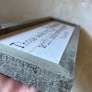 May include: A rustic wooden sign with a gray stain and a white background. The sign reads "Those who wander are not lost, with love always find your way home".