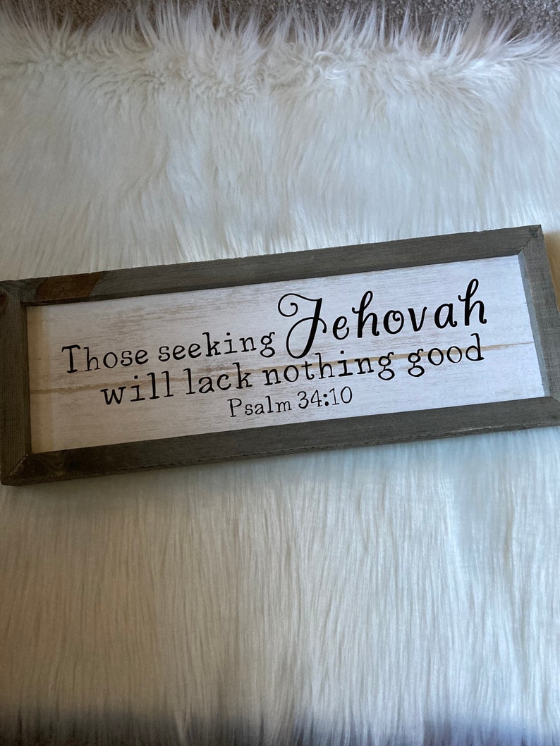 May include: A framed wood sign with a white background and black lettering. The sign reads "Those seeking Jehovah will lack nothing good Psalm 34:10".