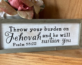 May include: A wooden sign with a white background and black text. The sign reads "Throw your burden on Jehovah and he will sustain you. Psalm 55:22".