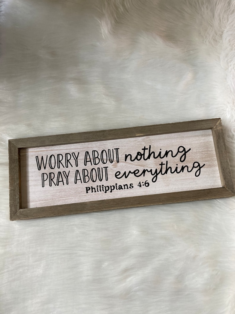 May include: Wooden sign with the text "Worry about nothing, pray about everything, Philippians 4:6" in black lettering.