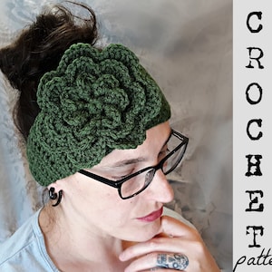 May include: A green crocheted headband with a large flower design. The headband is worn by a person with dark hair and glasses.