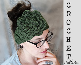 May include: A green crocheted headband with a large flower design. The headband is being worn by a person with dark hair and glasses.