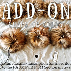 Puede incluir: Pompones de piel sint&eacute;tica en tonos marr&oacute;n y beige, con el texto "ADD-ON SNAPS OR CORDS!". La imagen muestra varios pompones con cordones y broches. Una etiqueta dice "6" LARGE".