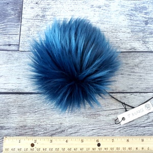 Puede incluir: Un pomp&oacute;n grande, esponjoso y redondo en tonos azules. El pomp&oacute;n de piel sint&eacute;tica mide aproximadamente 18 cm de di&aacute;metro. Una etiqueta adjunta al pomp&oacute;n dice "7" X-LARGE".