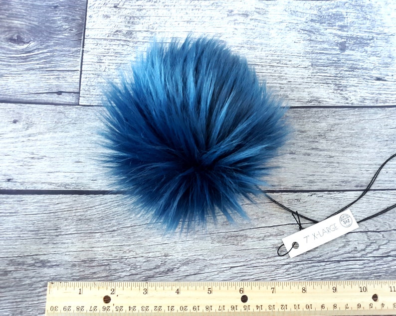Puede incluir: Un pomp&oacute;n grande, esponjoso y redondo en tonos azules. El pomp&oacute;n de piel sint&eacute;tica mide aproximadamente 18 cm de di&aacute;metro. Una etiqueta adjunta al pomp&oacute;n dice "7" X-LARGE".