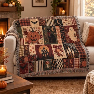 May include: A woven throw blanket featuring a patchwork design with Halloween motifs including a jack-o'-lantern, a black cat, a ghost holding a lantern, a haunted house, bats, candles, mushrooms, and floral patterns in shades of orange, black, and cream.