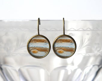 May include: A pair of dangle earrings with a round, gold-toned metal setting. Each earring features a colorful image of Jupiter, the largest planet in our solar system.