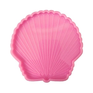 May include: Pink silicone mold shaped like a seashell with a detailed ribbed texture.