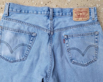 May include: Light blue denim jeans with the Levi Strauss & Co. 505 label visible. The jeans have two back pockets with the Levi's signature arcuate stitch design and a small red tab. The jeans are a classic style.