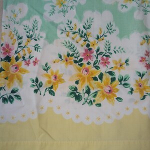 Pode incluir: Tecido floral com um padr&atilde;o repetido de flores amarelas e rosas, folhas verdes e formas brancas em forma de nuvem sobre um fundo verde claro. A borda inferior &eacute; amarela com uma borda branca ondulada.