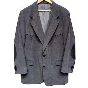 May include: A gray corduroy blazer with black elbow patches and black buttons. The blazer has a classic design with a notched lapel and two front pockets. The jacket is hanging on a wooden hanger.