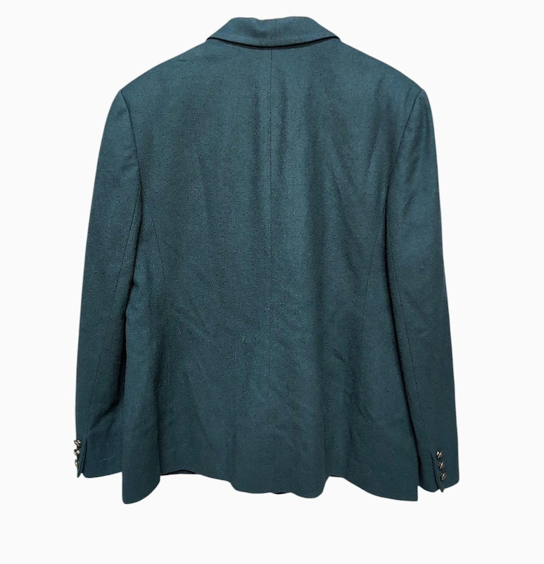 May include: A dark teal blazer with a classic notched lapel and two decorative buttons on each cuff. The back of the blazer is visible, showcasing the tailored design and fabric texture. The blazer is a solid color, suitable for various occasions.