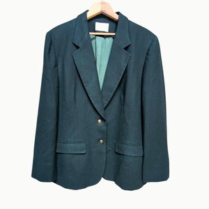 May include: Dark green blazer with a notched lapel, two front pockets, and gold-colored buttons. The blazer is hanging on a wooden hanger. The interior lining is a lighter shade of green.