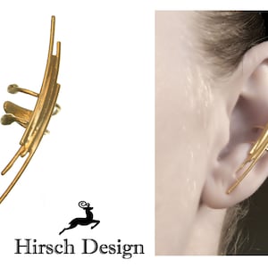 Può includere: Orecchino dorato con un design geometrico. L'orecchino è realizzato con sottili pezzi di metallo curvi disposti in un motivo a strati. L'orecchino viene indossato sulla parte superiore dell'orecchio.