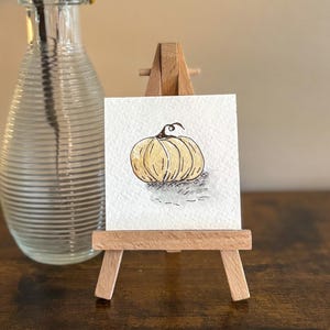 Miniatura de calabaza pintada con acuarela y caballete: decoración otoñal