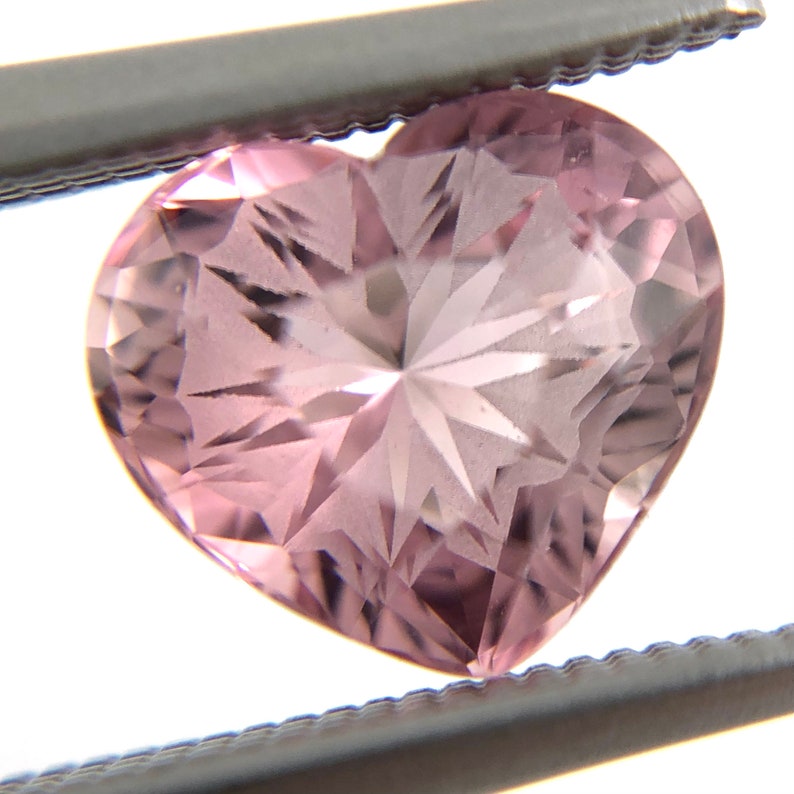 May include: A pink heart-shaped gemstone with a star-shaped pattern inside.