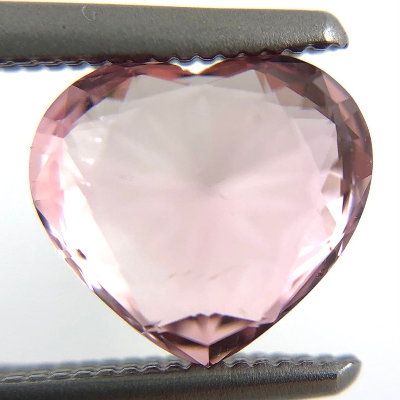 May include: A heart-shaped, light pink gemstone with a faceted cut.