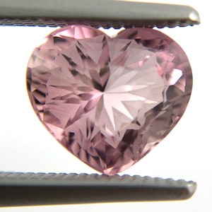 May include: A heart-shaped, faceted, pink gemstone with a starburst pattern.