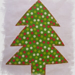 May include: A green felt Christmas tree with red and white polka dots. The tree is outlined in red stitching.