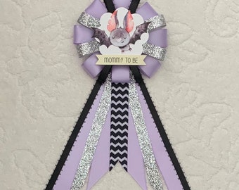 May include: Purple, black and silver ribbon rosette with a cute bat illustration and the text "mommy to be".