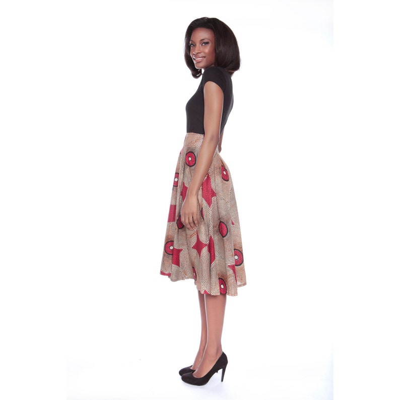 May include: A woman wearing a black short-sleeved top and a brown and red patterned skirt. The skirt has a flared silhouette and a geometric print.