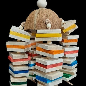 May include: A colorful bird toy with a coconut shell base and wooden blocks in various colors, including yellow, orange, red, blue, and green. The toy is suspended by a string and features wooden beads. The background is black.