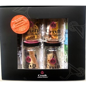May include: A black gift box containing four glass jars of cocktail infusions. Each jar has a black lid and a label that reads "Craft cocktail infusions." The box also has a sticker that says "Witches Brew Glitter Infusion Set."