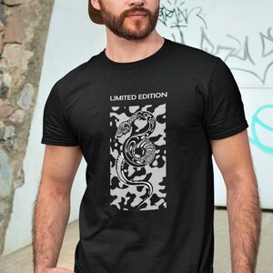 May include: Black t-shirt featuring a white graphic of a snake on a camouflage pattern. The text "LIMITED EDITION" is printed above the graphic.