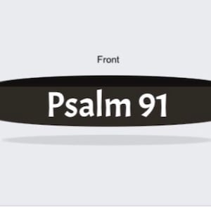 May include: A black, oval-shaped wristband with the text "Psalm 91" in white, centered on the band. The word "Front" is above the band. The wristband casts a shadow on a light gray background.