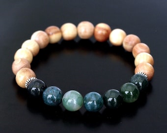 Puede incluir: Un brazalete de madera y ágata verde. El brazalete tiene un degradado de cuentas de madera, pasando de marrón claro a marrón oscuro. Las cuentas de ágata son de un verde intenso con un patrón moteado.
