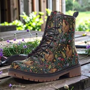 May include: A pair of black lace-up boots with a colorful floral and chicken pattern. The boots have a brown sole and heel, and are set on a wooden surface with gardening tools and flowers.