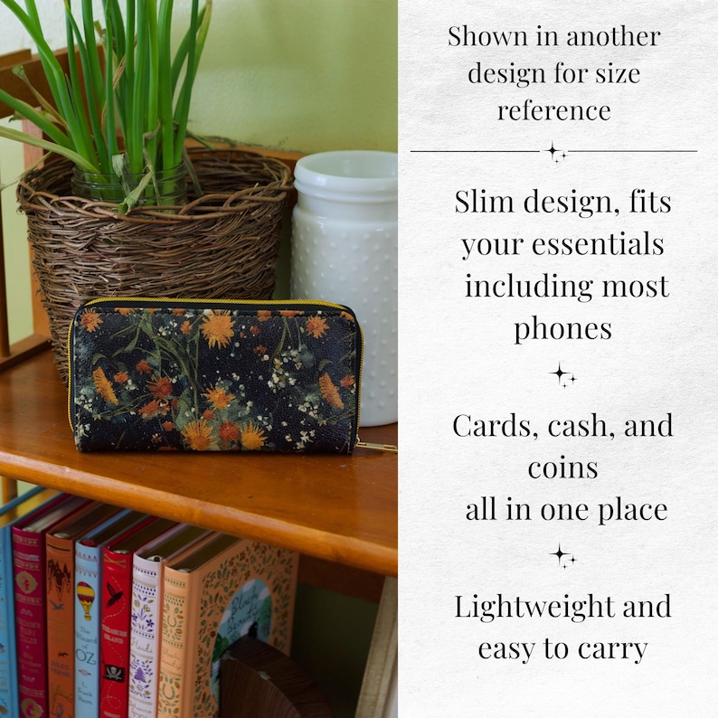 Op de afbeelding: Een zwarte bloemenportemonnee met een gele rits, op een houten plank. De portemonnee heeft een donkere achtergrond met oranje en gele bloemmotieven. De tekst zegt "Slim design, fits your essentials including most phones."