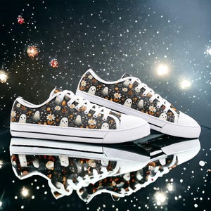 May include: A pair of black and white canvas shoes with a ghost and floral pattern. The shoes have white laces and a white sole.