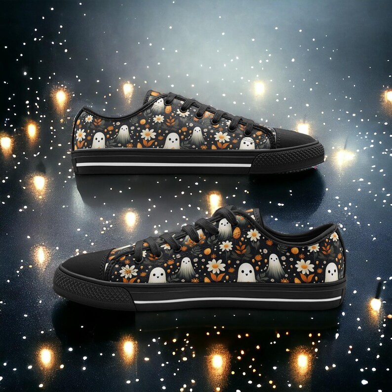 May include: Black canvas low-top sneakers with a white sole and a pattern of white ghosts and orange flowers on a black background.