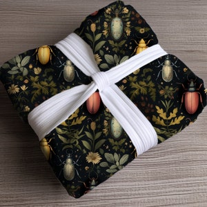 May include: Black fabric gift wrap with a repeating pattern of colourful beetles and flowers. The fabric is tied with a white ribbon.