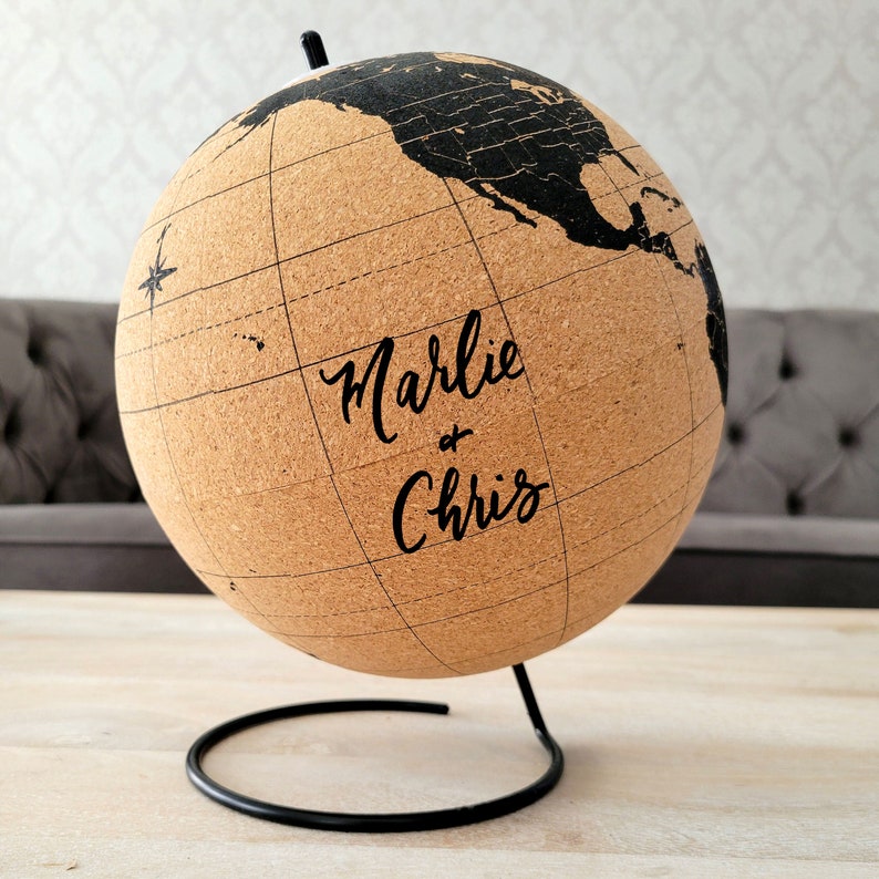 May include: Cork globe with a black metal stand. The globe has a world map printed on it and the text "Marlie & Chris" is written on the front.