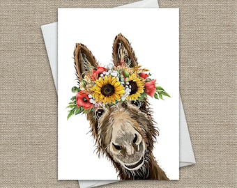 May include: A brown donkey with a flower crown made of sunflowers, red poppies, and white flowers. The donkey is looking at the camera with a smile.