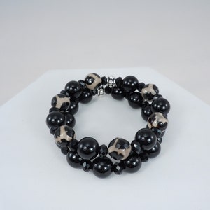 May include: A double-strand bracelet with black and white agate beads and black crystal beads. The bracelet has a silver clasp.