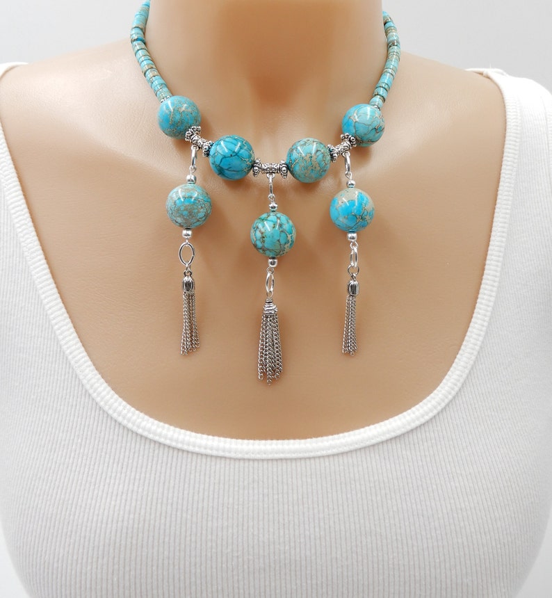 Pu&ograve; includere: Una collana statement turchese e argento con grandi perle rotonde e nappe pendenti. La collana &egrave; realizzata con pietre turchesi e metallo argentato.