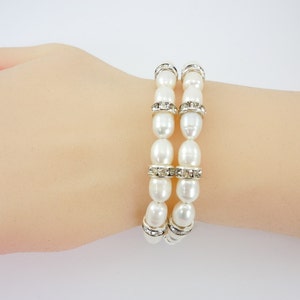 May include: Two white pearl bracelets with silver accents and clear rhinestone embellishments.