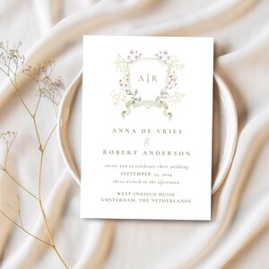 May include: Wedding invitation featuring a floral design and the initials "A" and "R" in a crest. The invitation is for Anna de Vries and Robert Anderson, to be held on 14 September 2024, at three o'clock in the afternoon at West-Indisch Huise in Amsterdam, The Netherlands.