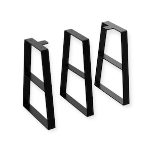May include: Three black metal table legs. Each leg has a rectangular frame with a horizontal support bar and a top plate with pre-drilled holes for mounting. The legs are designed for furniture construction and have a modern, minimalist aesthetic.