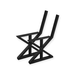 May include: Two black metal chairs with a geometric design. The chairs have a modern aesthetic, featuring angled legs and a minimalist style. The seat and back are formed by the frame.