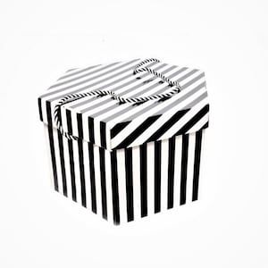 May include: A black and white striped hexagonal gift box with a black ribbon handle.